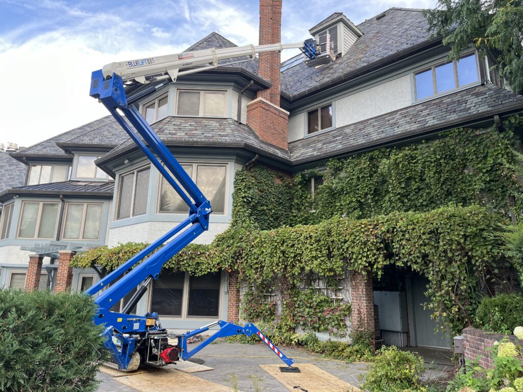 This is an image of a Bluelift B85, a brand of atrium boom lifts, reaching the roof of a house.