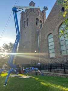 This is an image of a Atrium Boom Lift, Bluelift, being used to work on a roof of a brick church.